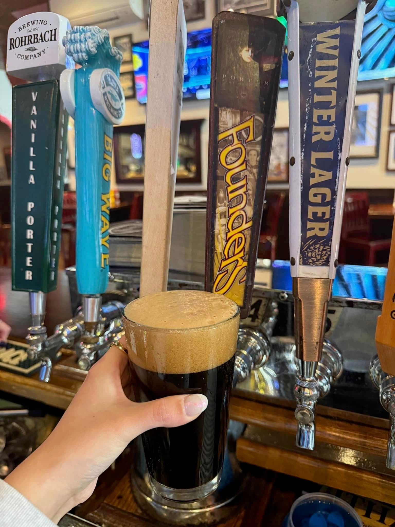 Dark porter or stout with foamy head at bar with Founders and Winter Lager taps